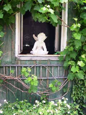 Engelsskulptur dient als Blickfang für die verträumte Gartenhütte